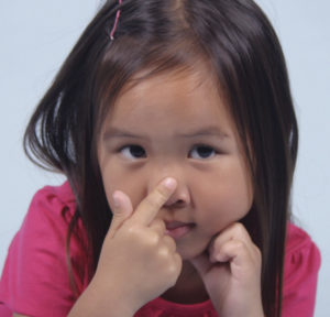 child touching their nose