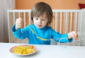 child stringing pasta