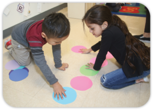 2 children playing with big dots on floor