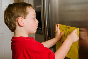 boy displaying art on refrigerator