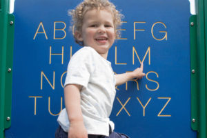 child pointing to a letter M
