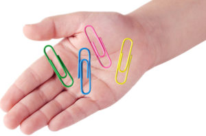 child's hand with paper clips