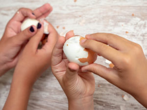 children's hands peeling a boiled egg