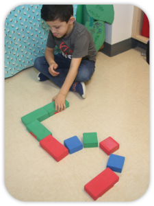 child making a numeral 5 with blocks