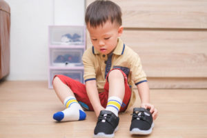 Little boy putting on his shoes