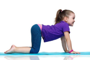Little girl practicing yoga pose standing on knees