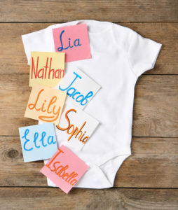 Paper notes with different baby names and child's bodysuit